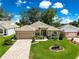 Single-story home featuring a well-manicured lawn, mature trees, and inviting front entrance at 1010 Sierra Blanca Ct, Lady Lake, FL 32159