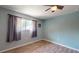 Bright bedroom with light blue walls, laminate floors, ceiling fan and large window with curtains at 11418 Lake Eustis Dr, Leesburg, FL 34788