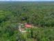 Aerial view of a secluded residence with a red roof nestled among trees and a driveway, promising privacy and tranquility at 12288 Sw 35Th Dr, Webster, FL 33597