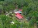 Aerial shot showcases a home with a red roof and a split rail fence surrounded by lush trees, near a shed and car port at 12288 Sw 35Th Dr, Webster, FL 33597