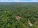 Expansive aerial view of a home with a red roof nestled within a lush forest setting, creating a secluded retreat at 12288 Sw 35Th Dr, Webster, FL 33597