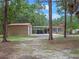 Property featuring a two-car garage, a carport, and a home with a red roof, surrounded by mature trees at 12288 Sw 35Th Dr, Webster, FL 33597