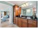 Bathroom with wooden cabinets, granite countertops, and stylish lighting fixtures over the sink at 1376 Birdsong Pl, The Villages, FL 32163