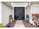 Inviting entryway with a screened front door, planters, and a view into the living area at 1376 Birdsong Pl, The Villages, FL 32163