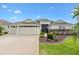 An exterior view of a charming single-Gathering home featuring an attached three car garage and mature landscaping at 1376 Birdsong Pl, The Villages, FL 32163