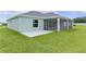 The exterior backyard view showcasing a screened-in patio with a concrete patio and lush green lawn at 1449 Jeremy Cir, The Villages, FL 34762