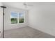 Bright bedroom featuring a ceiling fan, carpeted floor, and a large window with neighborhood views at 1449 Jeremy Cir, The Villages, FL 34762