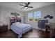 Well-lit bedroom featuring a plaid bedspread, dark wood floors, and bright windows overlooking the neighborhood at 14501 Wabasso Loop, Winter Garden, FL 34787