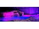 A beautiful pool with a rock slide feature, enhanced by vibrant purple and blue lights, perfect for evening relaxation at 14501 Wabasso Loop, Winter Garden, FL 34787