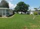 Manicured lawn with mature tree in front of charming single-story home under a sunny sky at 146 Hibiscus Way, Leesburg, FL 34748