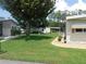 Well-maintained lawn, mature trees, landscaping, and community homes at 146 Hibiscus Way, Leesburg, FL 34748