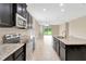Modern kitchen with dark cabinets, stainless steel appliances, and granite countertops flows into the dining area at 15531 Waterleigh Cove Dr, Winter Garden, FL 34787