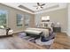 Beautifully staged primary bedroom featuring a tray ceiling, wood flooring, and an abundance of natural light at 15531 Waterleigh Cove Dr, Winter Garden, FL 34787