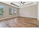 Bright primary bedroom featuring a tray ceiling, wood flooring, and large windows providing ample natural light at 15531 Waterleigh Cove Dr, Winter Garden, FL 34787
