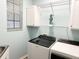 Bright laundry room features a window, washer and dryer, and shelving for storage at 1676 Van Buren Way, The Villages, FL 32162