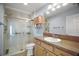 Bright bathroom features a glass shower, toilet, vanity, and wooden storage with shelves at 16827 Se 92Nd Lance Ct, The Villages, FL 32162