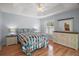 Light-filled bedroom with hardwood floors, a decorative tray ceiling, and plantation shutters at 16827 Se 92Nd Lance Ct, The Villages, FL 32162