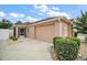 Beige single-story home featuring an attached two-car garage and lush landscaping at 16827 Se 92Nd Lance Ct, The Villages, FL 32162
