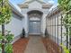 The front door of the home is surrounded by a metal fence and lush landscaping at 1706 Augustine Dr, The Villages, FL 32159