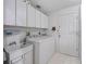 Laundry room with washer, dryer, utility sink, white cabinets, and exterior door at 1706 Augustine Dr, The Villages, FL 32159