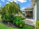 Landscaped backyard with lush plants, mature tree, and stone paver patio with awning at 17324 Se 82Nd Pecan Ter, The Villages, FL 32162