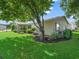 Backyard of a home with a lawn, landscaping, and a large shade tree at 17324 Se 82Nd Pecan Ter, The Villages, FL 32162