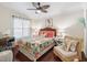 Bright bedroom with a ceiling fan, tropical-themed bedding, and side tables with lamps at 17324 Se 82Nd Pecan Ter, The Villages, FL 32162
