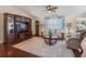Comfortable living room featuring wood floors, ceiling fan, entertainment center, and plush seating at 17324 Se 82Nd Pecan Ter, The Villages, FL 32162