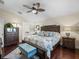 Comfortable main bedroom boasts a beautiful bed, dark hardwood floors and a light blue bench at 17324 Se 82Nd Pecan Ter, The Villages, FL 32162