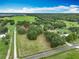 Aerial view showcasing the property's location with surrounding greenery, trees, neighboring homes, and distant lake views at 17670 Se 283Rd Ave, Umatilla, FL 32784