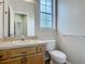 Well-lit bathroom featuring a vanity, toilet, mirror, and a window for ventilation at 17670 Se 283Rd Ave, Umatilla, FL 32784