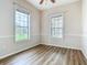 Bright bedroom featuring wood-look floors and two windows with views of the yard at 17670 Se 283Rd Ave, Umatilla, FL 32784