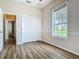 A comfortable bedroom featuring wood-look floors, closet, and window with backyard views at 17670 Se 283Rd Ave, Umatilla, FL 32784