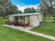 Exterior view of mobile home with wooden porch, paved walkway, and green lawn at 17670 Se 283Rd Ave, Umatilla, FL 32784