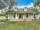 Charming home with a welcoming front porch, dormer windows, and a well-maintained lawn with mature shade trees at 17670 Se 283Rd Ave, Umatilla, FL 32784