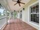 Inviting front porch with tile flooring, ceiling fans, and white railing overlooking the landscaped yard at 17670 Se 283Rd Ave, Umatilla, FL 32784