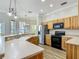 Well-equipped kitchen with wood cabinets, stainless steel appliances, and a breakfast bar overlooking the living area at 17670 Se 283Rd Ave, Umatilla, FL 32784