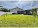 View of a spacious backyard featuring green grass, a screened lanai, and a modern home at 1861 Remembrance Ave, St Cloud, FL 34769