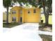 Yellow two-story home featuring a front yard with mature trees and an attached two-car garage at 2007 Country Brook Ave, Clermont, FL 34711