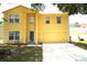 Two-story yellow home with an attached garage, well-maintained lawn and mature trees at 2007 Country Brook Ave, Clermont, FL 34711