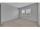 A cozy bedroom with neutral walls, carpet, and two windows with blinds allowing natural light to illuminate the space at 2147 Timber Creek Ln, Clermont, FL 34715