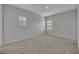 A cozy bedroom with neutral walls, carpet, two windows with blinds, baseboards, and an overhead light fixture at 2147 Timber Creek Ln, Clermont, FL 34715