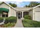 Charming home entrance with a decorative door, landscaped garden, and attached garage at 215 Chula Vista Ave, The Villages, FL 32159