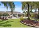 Expansive backyard with a screened lanai, concrete patio, and tropical landscaping under a blue sky at 2312 Nackman Pl, The Villages, FL 32162