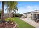 Lush backyard oasis featuring palm trees, a patio with outdoor seating, and a well-manicured lawn at 2312 Nackman Pl, The Villages, FL 32162
