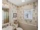 Bathroom features a shower and tub combination with a vanity and sink. Palm tree wallpaper at 2312 Nackman Pl, The Villages, FL 32162