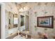 Bright bathroom features stylish palm tree wallpaper, a vanity and sink, and a framed mirror at 2312 Nackman Pl, The Villages, FL 32162