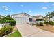 Charming home with a well-manicured yard and driveway, complemented by a white picket fence and lush landscaping at 2317 Whisper St, The Villages, FL 32162
