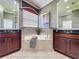 Bathroom boasts double sinks, a soaking tub with tile surround, tile flooring, and a stylish window treatment at 243 Bayou Bend Rd, Groveland, FL 34736