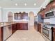 Bright kitchen boasts stainless steel appliances, granite countertops, tile flooring, and archway to other rooms at 243 Bayou Bend Rd, Groveland, FL 34736